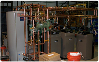 A mechanical room with boilers, pumps and copper piping