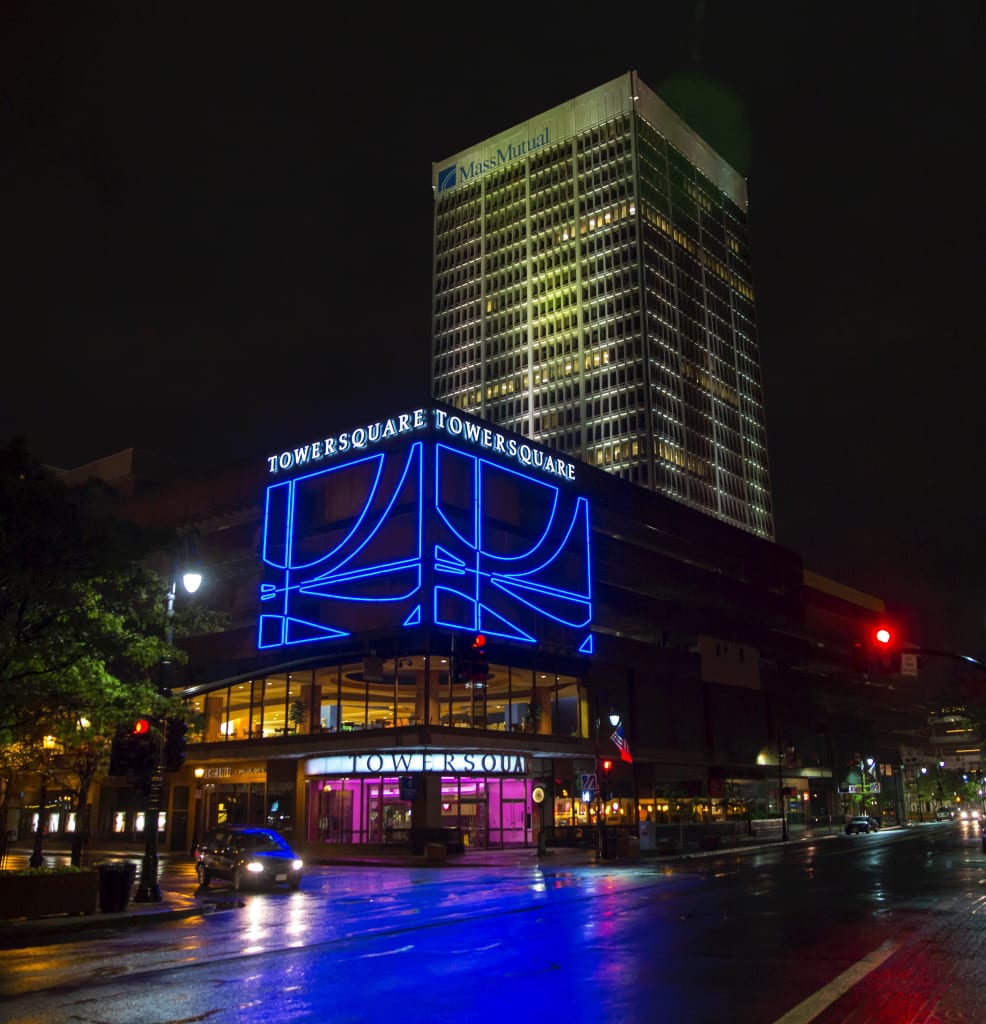 Downtown high-rise at night with a blue illuminated sign structure