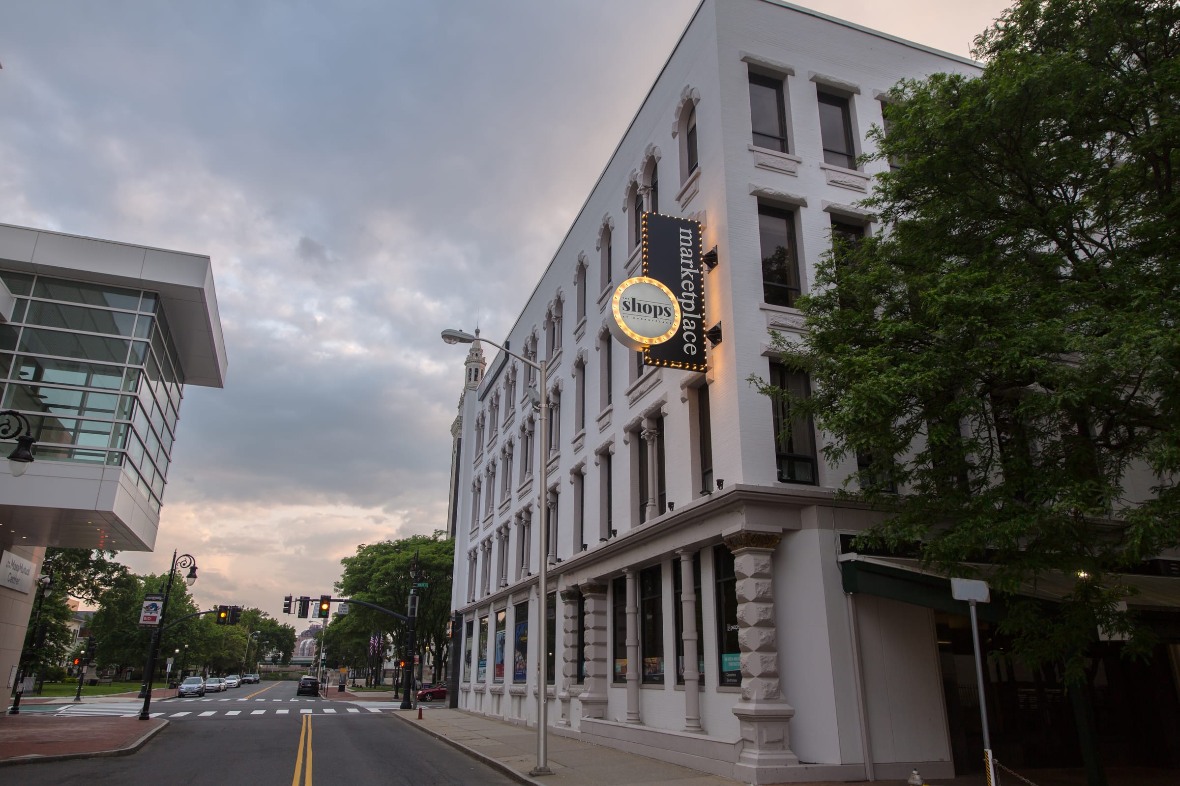 Round projecting sign on a historic white downtown building at dusk