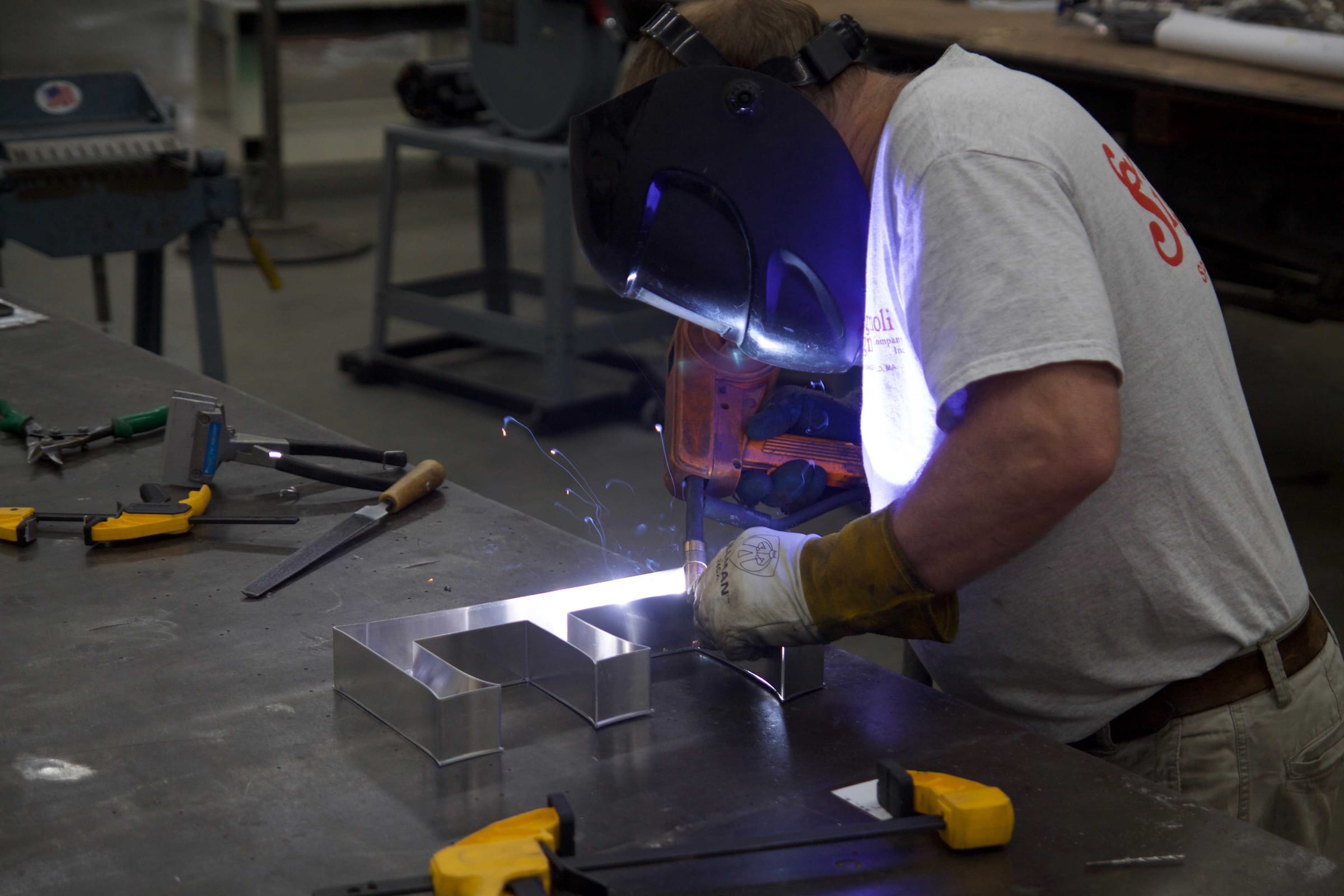An Agnoli fabricator welding a metal channel letter on the shop bench