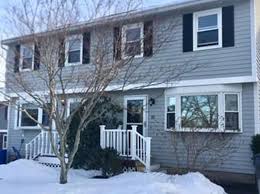 Two-story New England duplex with a front porch in winter snow