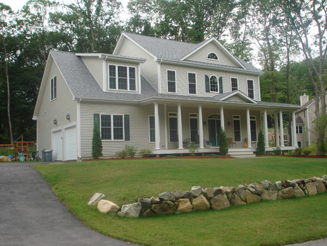 A colonial house with a stone wall and a wide front lawn, from AJ Electric's own photographs