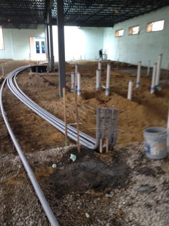 Conduit sweeps turning up out of the dirt floor of a building under construction