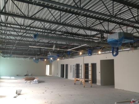 Overhead conduit and lighting in a steel frame interior nearing completion