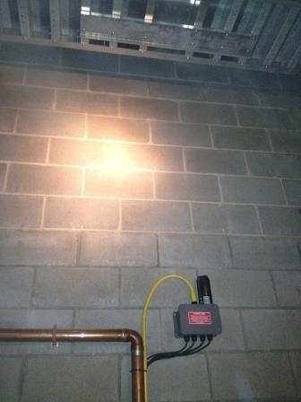 A lit fixture and a mounted device on a bare block wall
