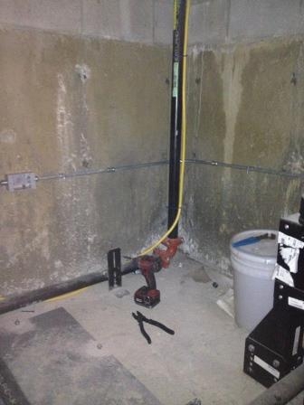 A conduit run dropped down a concrete wall to a device box