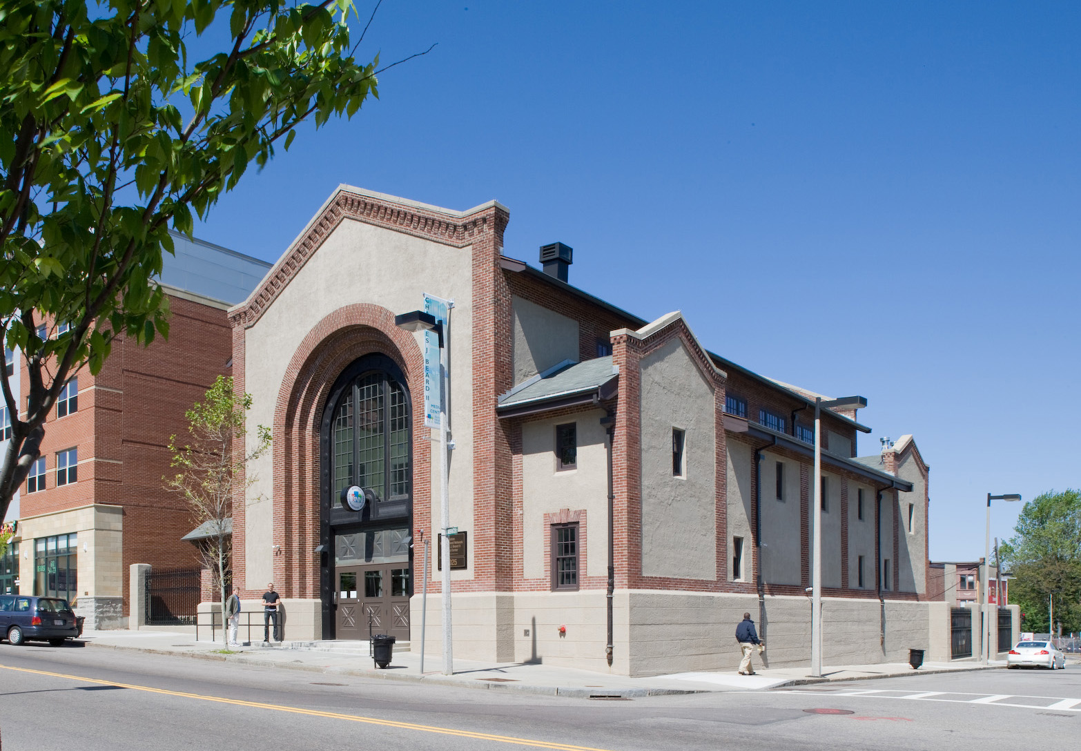 The restored historic substation on a clear day: brick and stucco gable with a large arched window, Roxbury