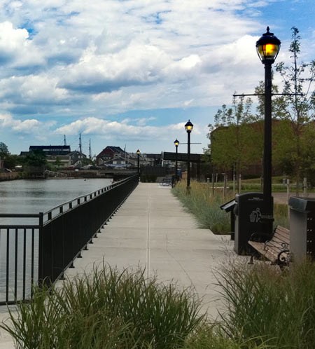 Lamp posts standing along a waterfront walkway under a bright sky