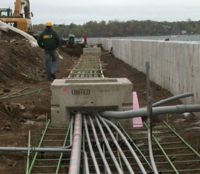 A crew member walking a formed concrete structure with conduit runs laid in ahead of a pour