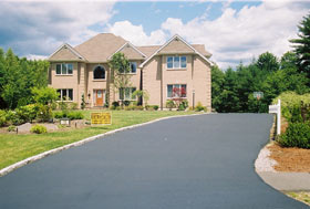 Freshly sealcoated residential driveway leading to a two car garage
