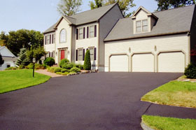 Freshly sealcoated driveway in front of a colonial house