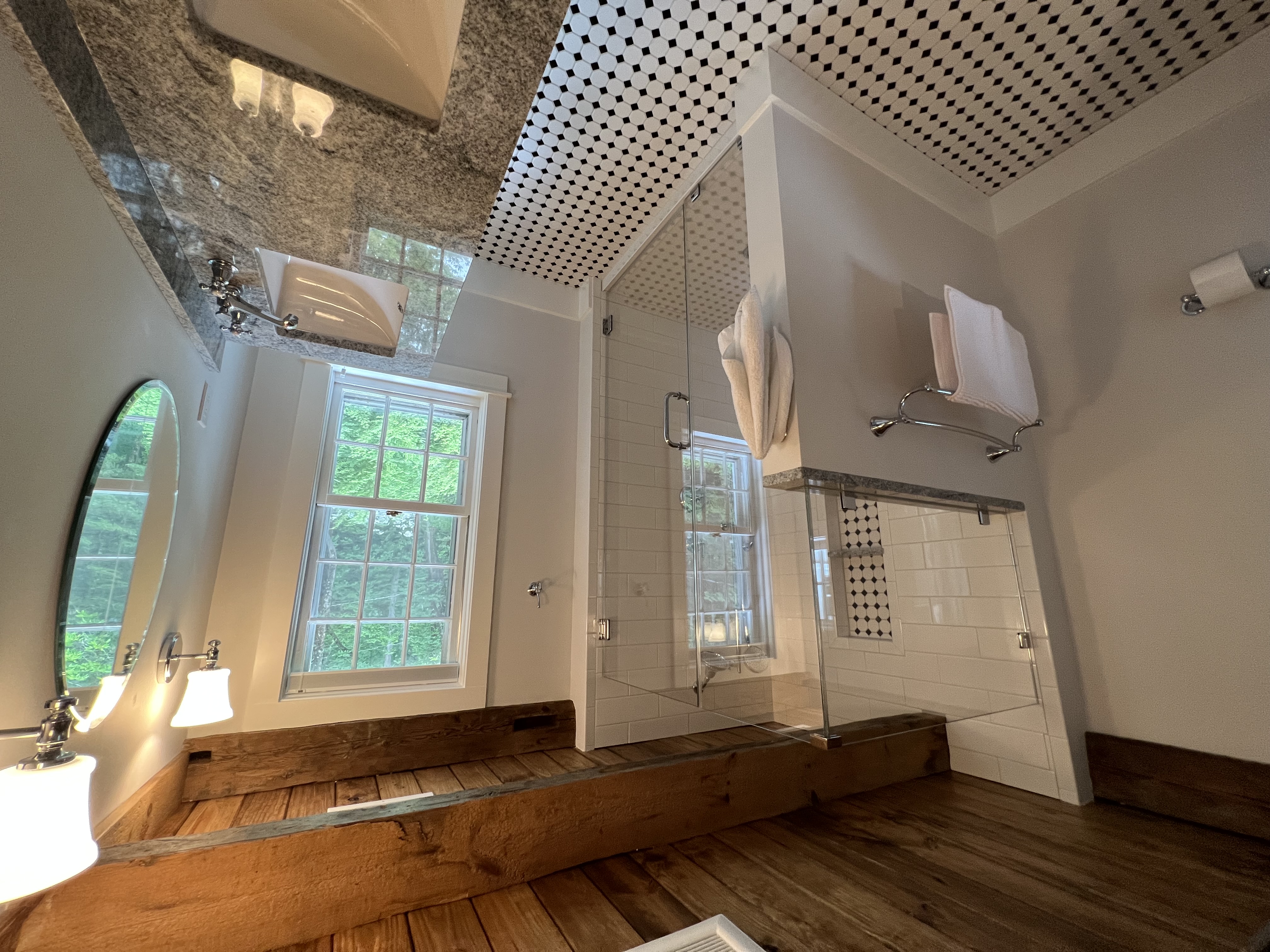 Finished bathroom with a glass shower, subway tile, a black and white hex tile floor, a stone double vanity and an exposed rough sawn timber beam ceiling