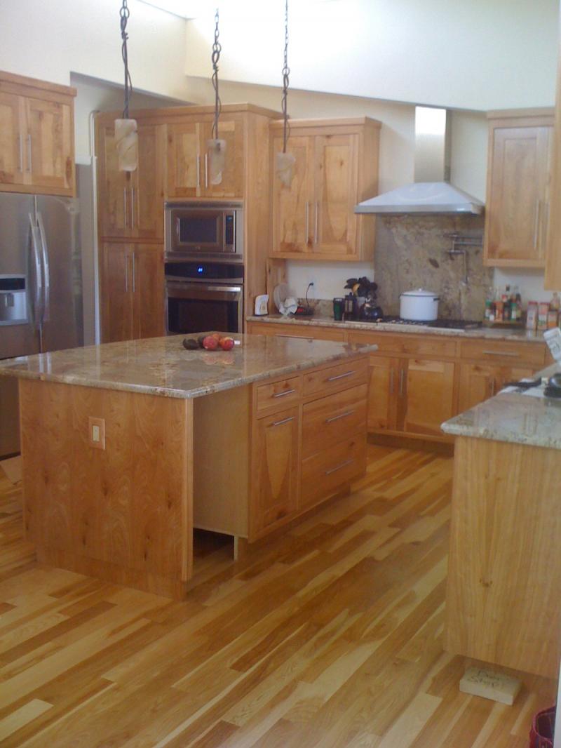 Open kitchen with birch cabinets, a granite island and wide plank hardwood flooring