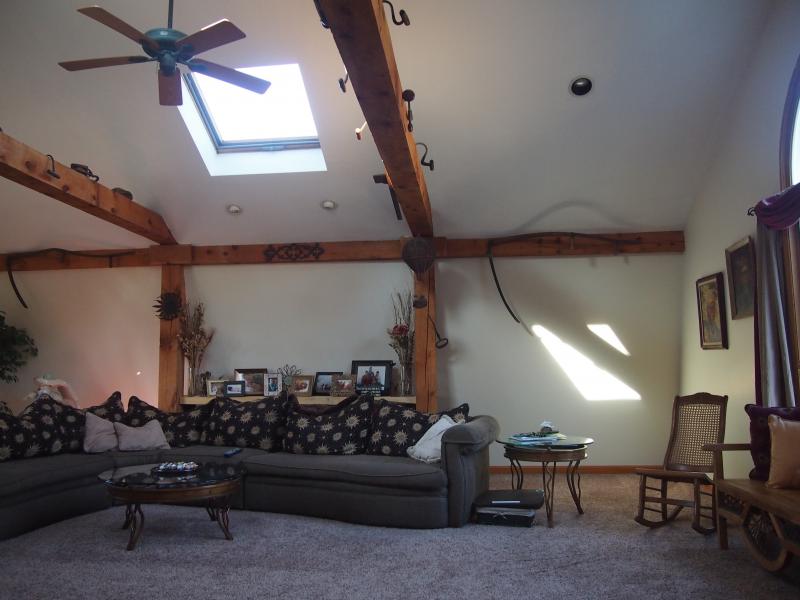 Living room with exposed timber beams, a vaulted ceiling and a skylight