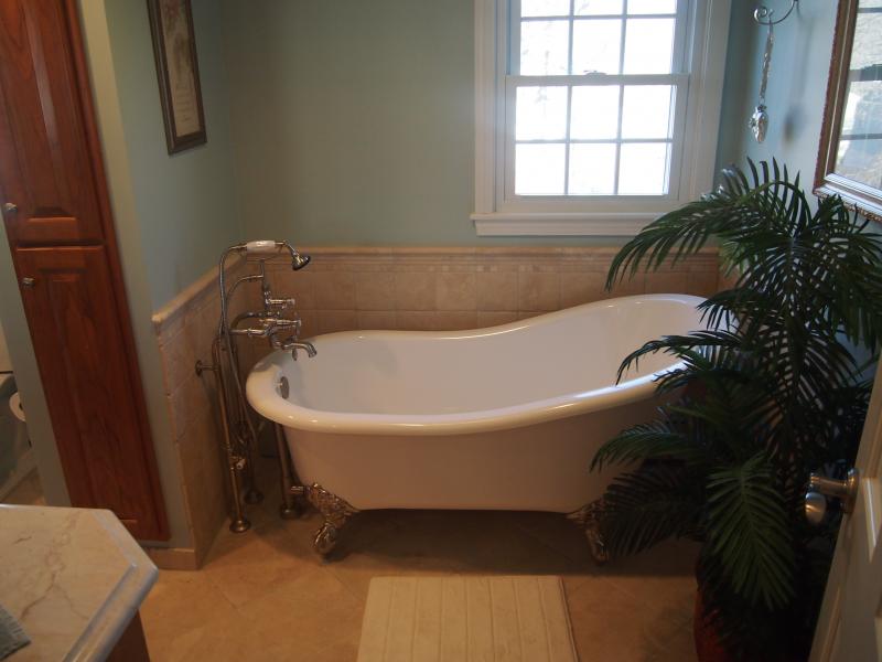 Bathroom with a slipper tub, floor mounted fixtures and tiled wainscot