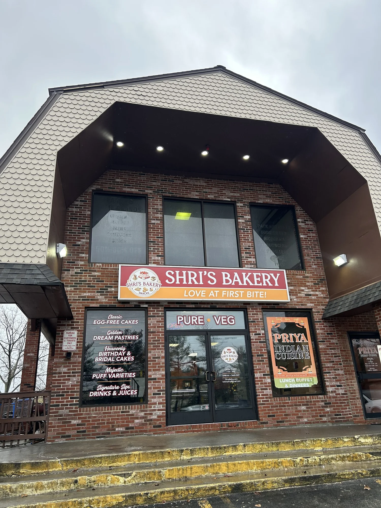 Shri's Bakery storefront at dusk with the exterior downlights lit