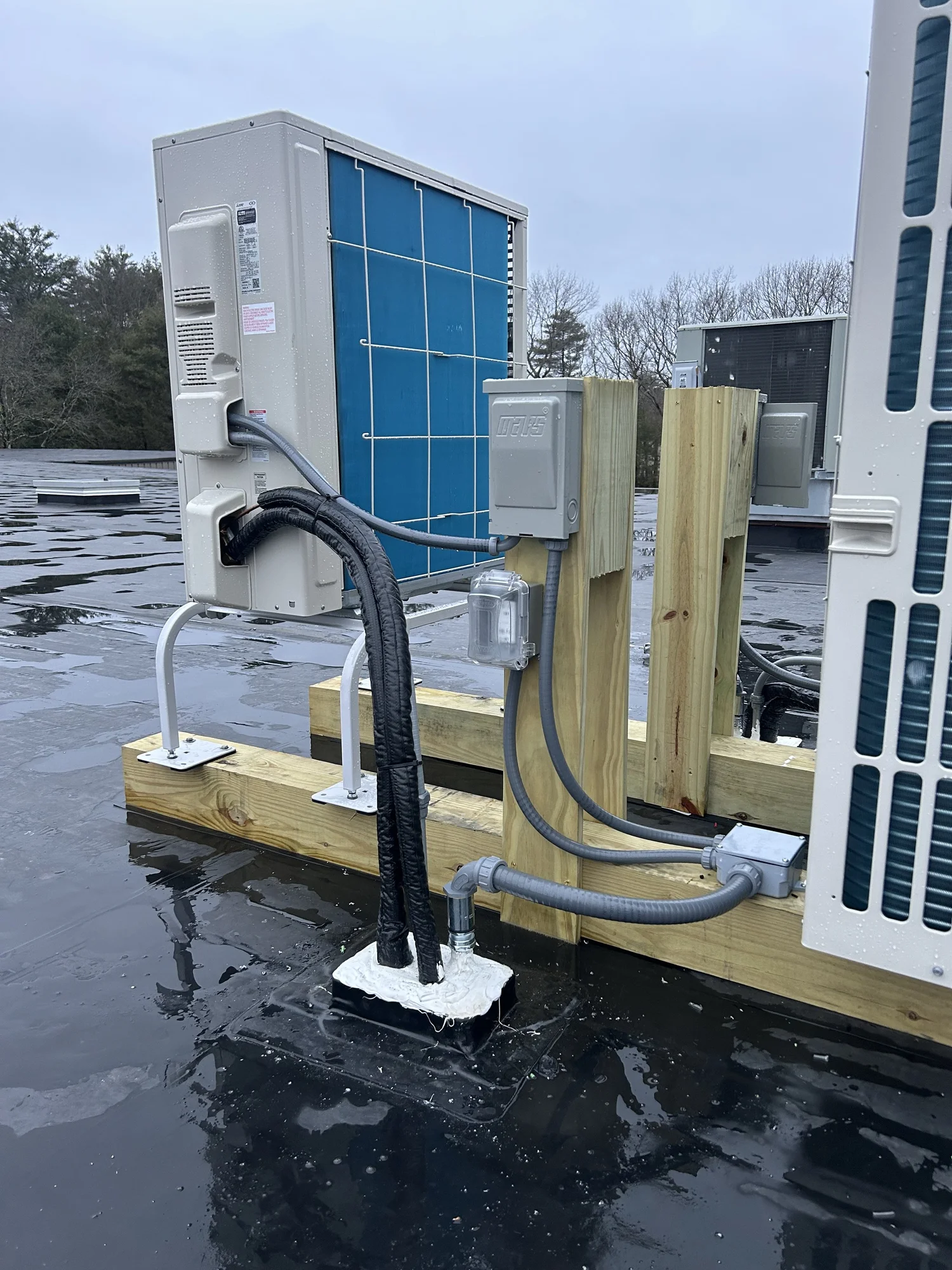 Rooftop mini-split condensers set on sleepers over a wet membrane roof