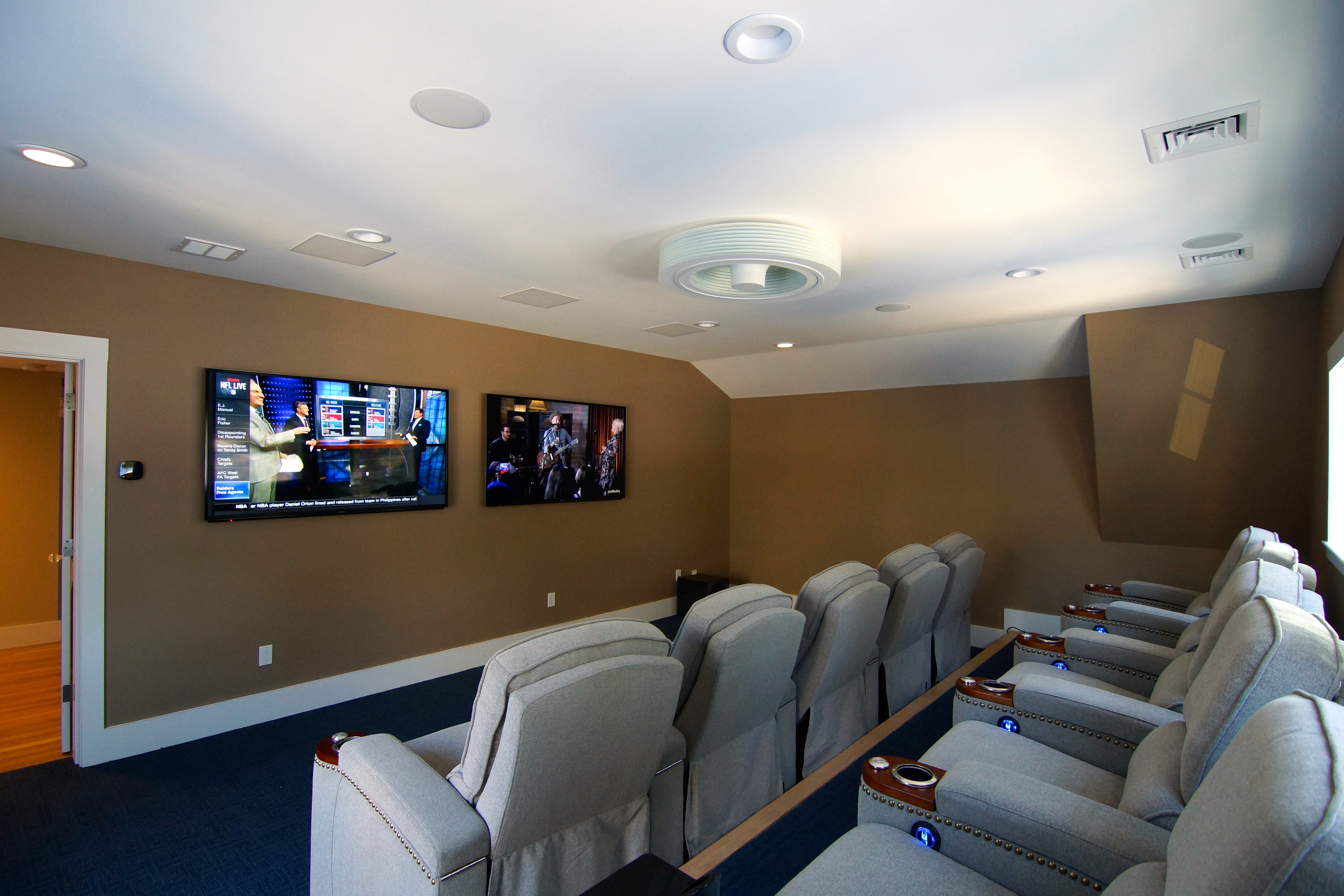 A private home theater with tiered reclining seats and two wall screens.