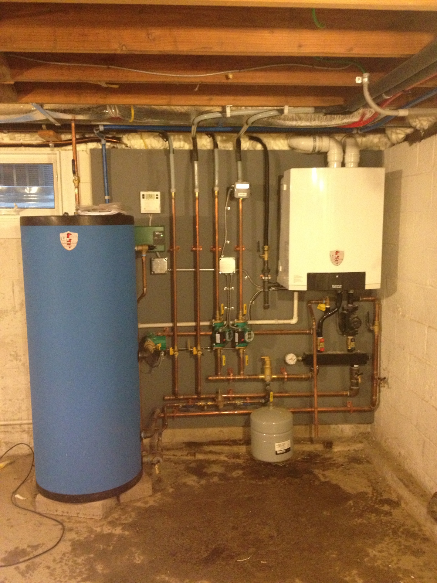 A wall-hung boiler, indirect tank and copper manifold on a painted backboard