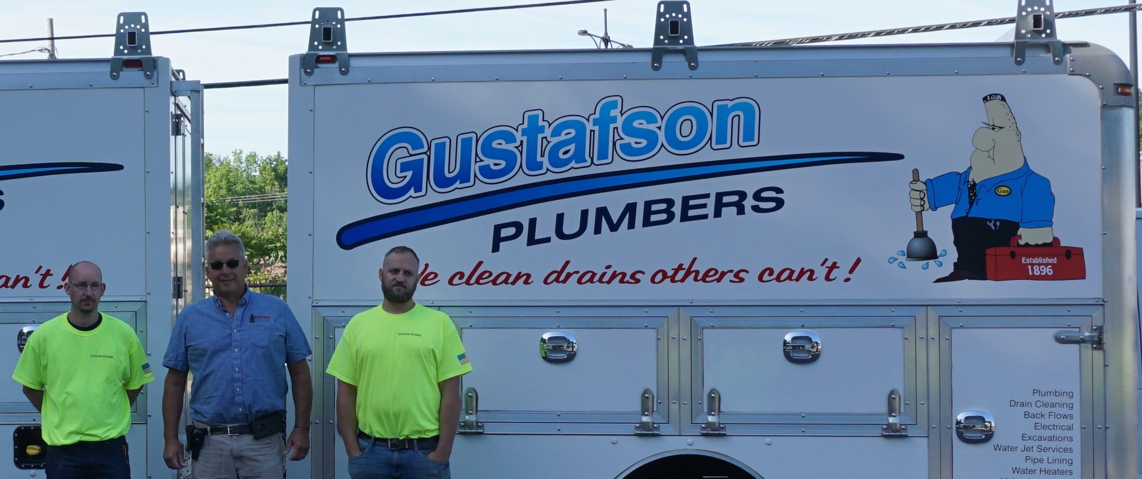 Three Gustafson crew members in front of a box truck with the Gustafson Plumbers lettering