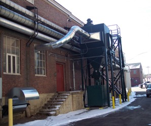 A dust collector and ducting beside a brick building