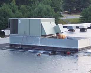 A mechanic working on a rooftop unit