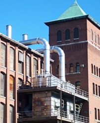 Ductwork rising up a brick mill building