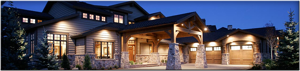 A stone-and-timber hillside home lit inside and out at twilight
