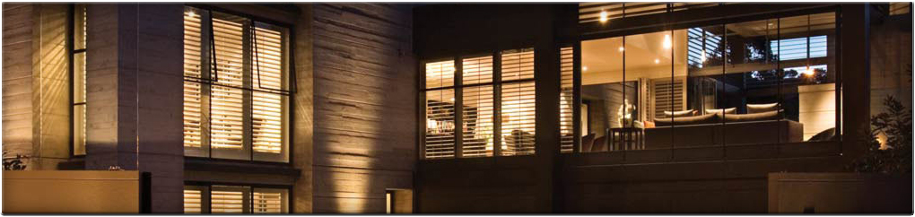 Warm light glowing through tall windows of a modern home at night