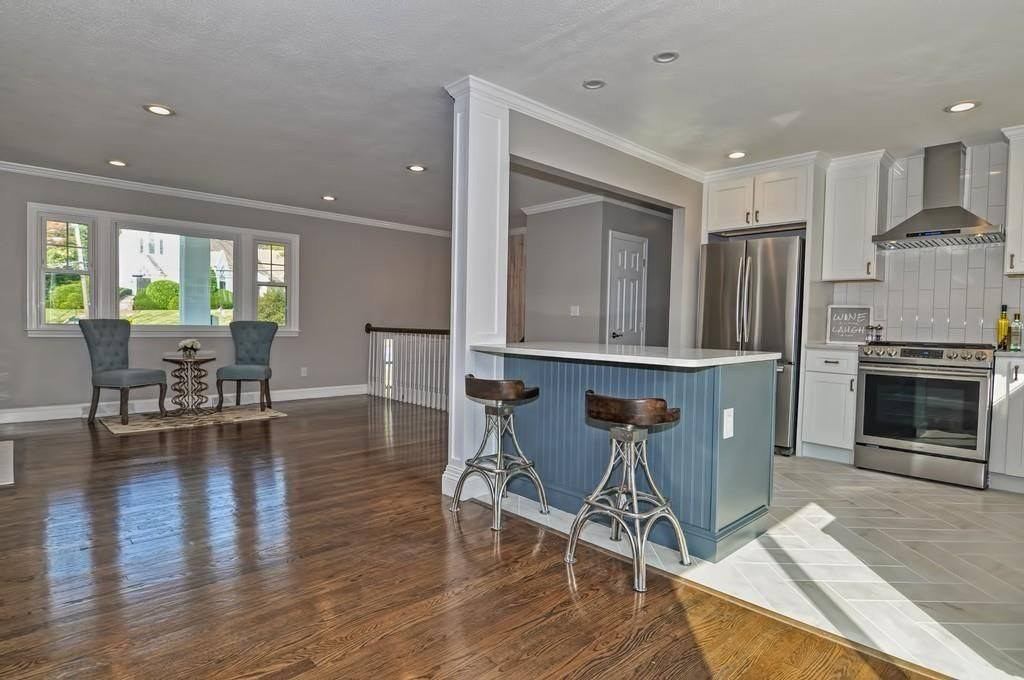 An open kitchen and dining room with a blue painted peninsula and metal counter stools
