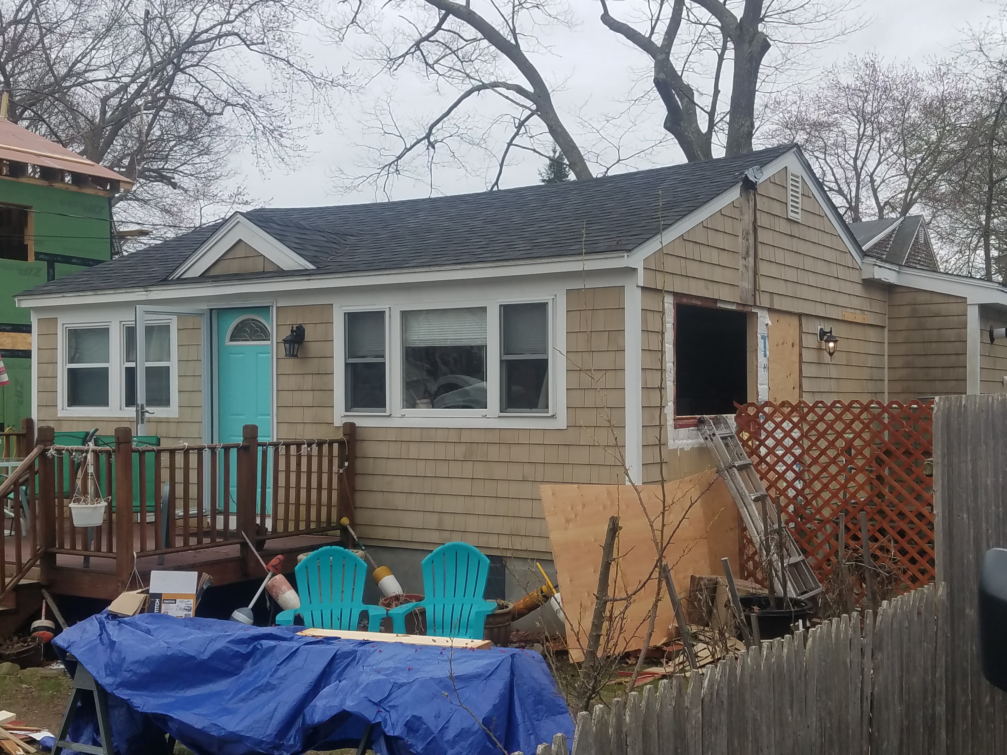 The cottage before work, with worn shingles, an old deck and an opening cut in the end wall