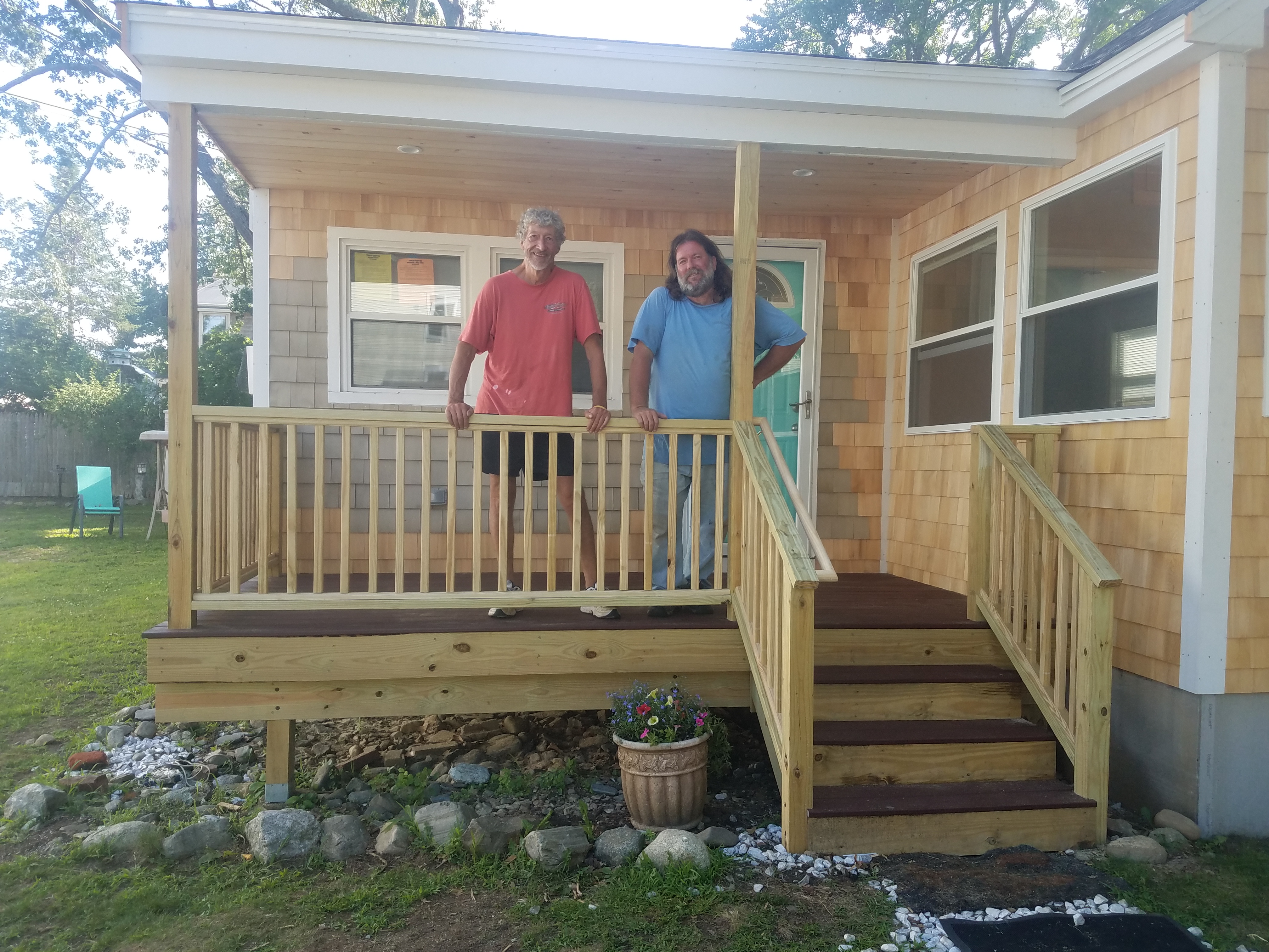 Two carpenters standing on the finished porch of the cottage