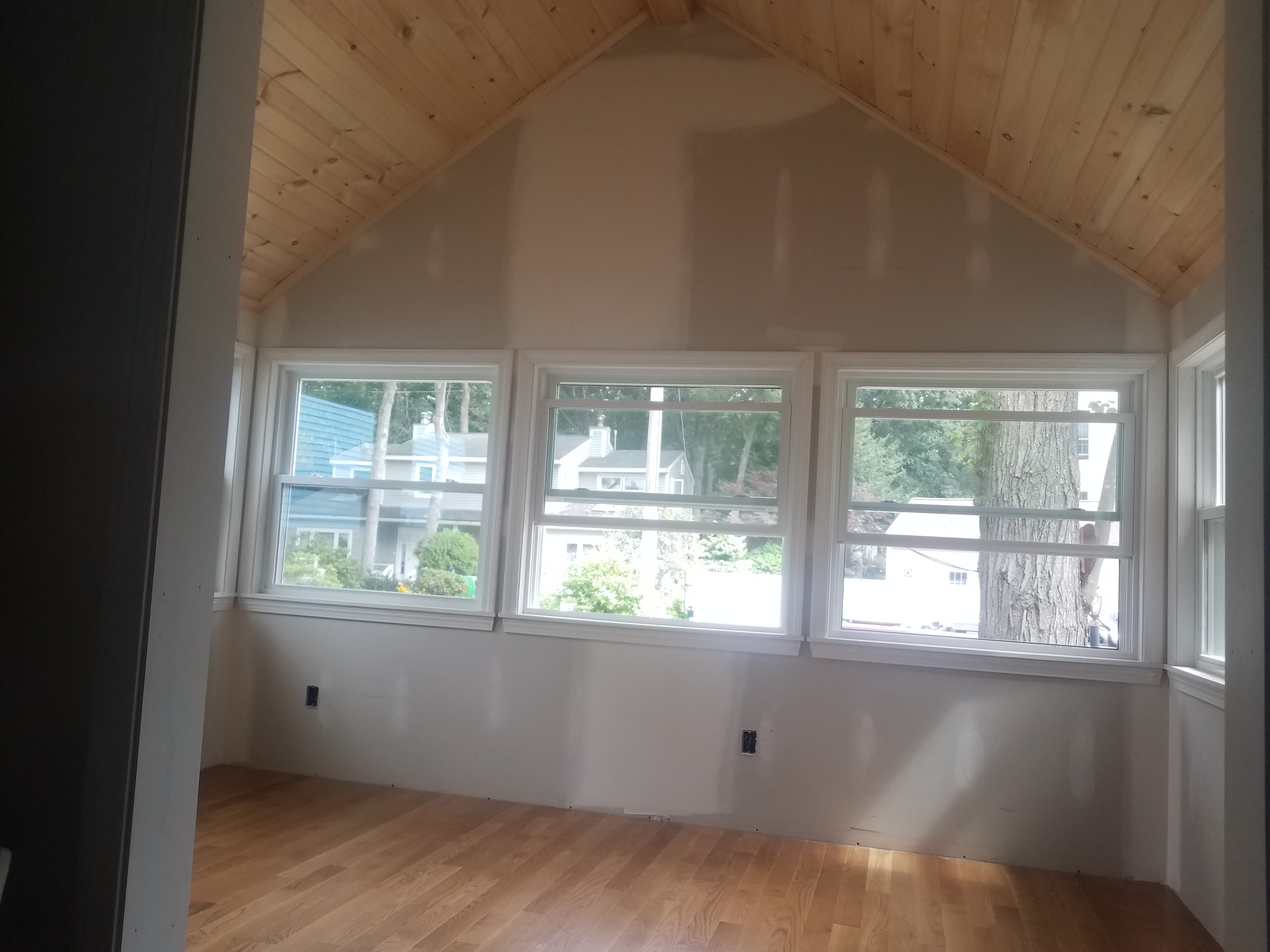 A finished room with a vaulted pine board ceiling, three new windows and a new hardwood floor