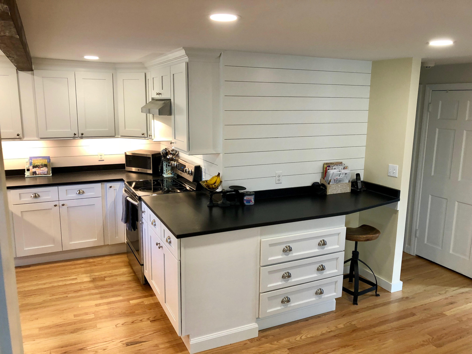 White shaker kitchen with black counters and a shiplap wall