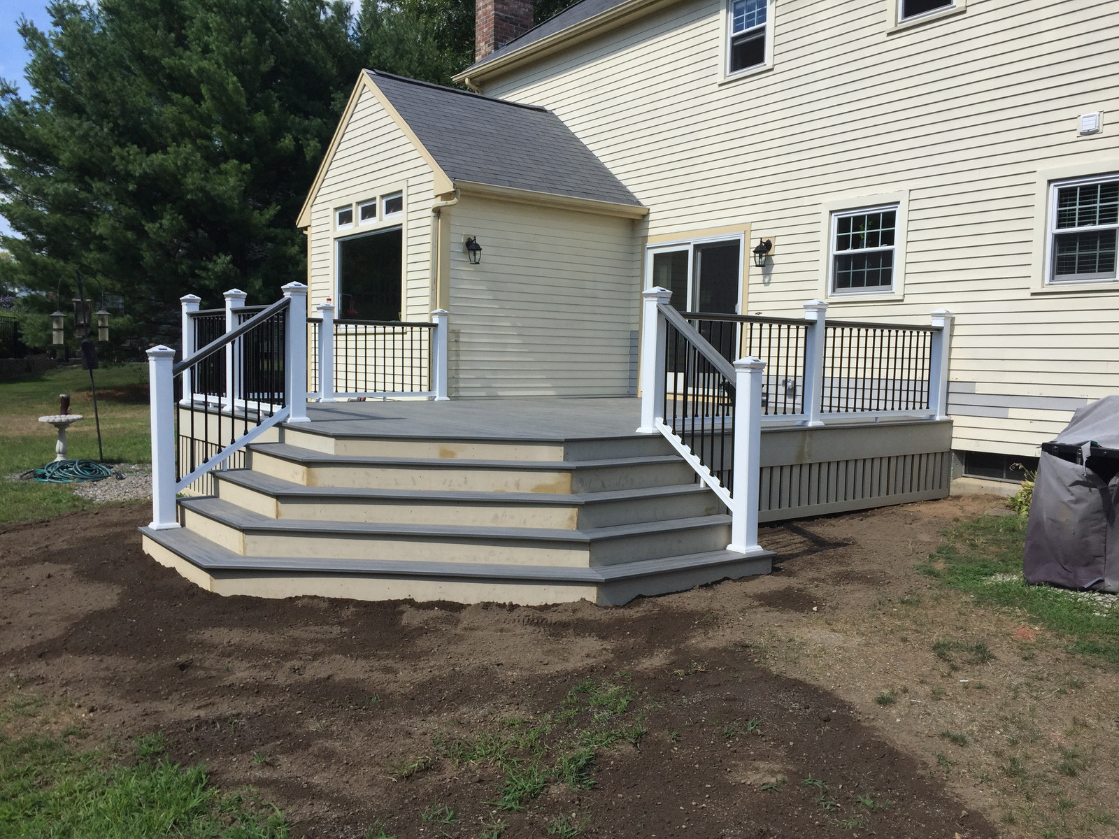 The finished deck with wide wraparound stairs and white rails