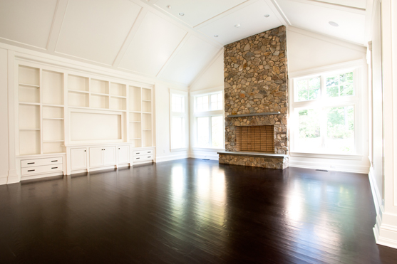 Great room with a stone chimney breast rising to a vaulted ceiling, flanked by painted built-ins