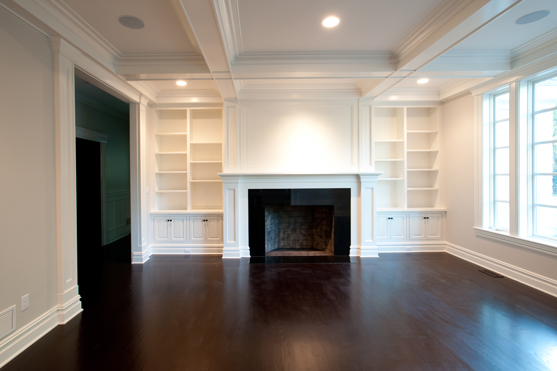 Room with a paneled fireplace wall, wainscot and dark stained floor