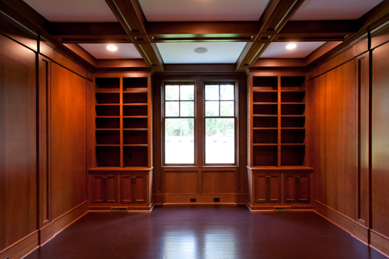 Mahogany paneled library with fitted shelving and a coffered ceiling