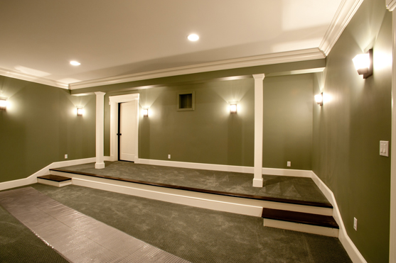 Home theater with green walls, paneled columns and tiered seating platforms