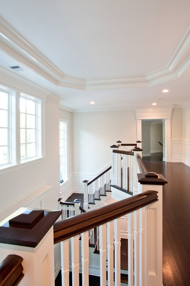 Upper stair landing with white balusters, a dark handrail and an open overlook