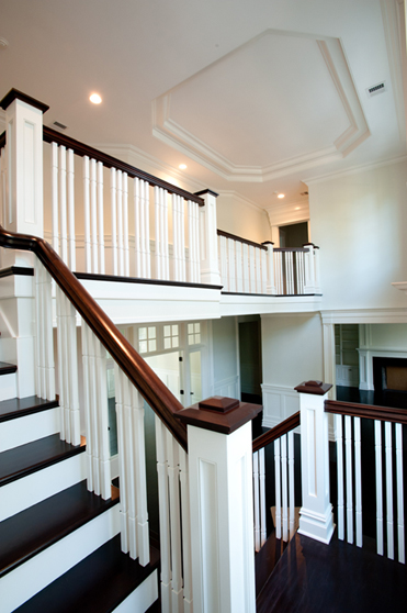 Painted staircase with white risers, dark treads and a two story stair hall
