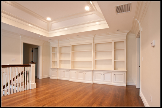 Painted built-in bookcases and cabinet bases running a full wall under a tray ceiling
