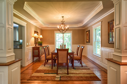 Formal dining room with a chandelier, tray ceiling and paneled wainscot