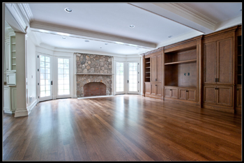 Great room with a stone fireplace, beamed ceiling and stained built-in cabinetry