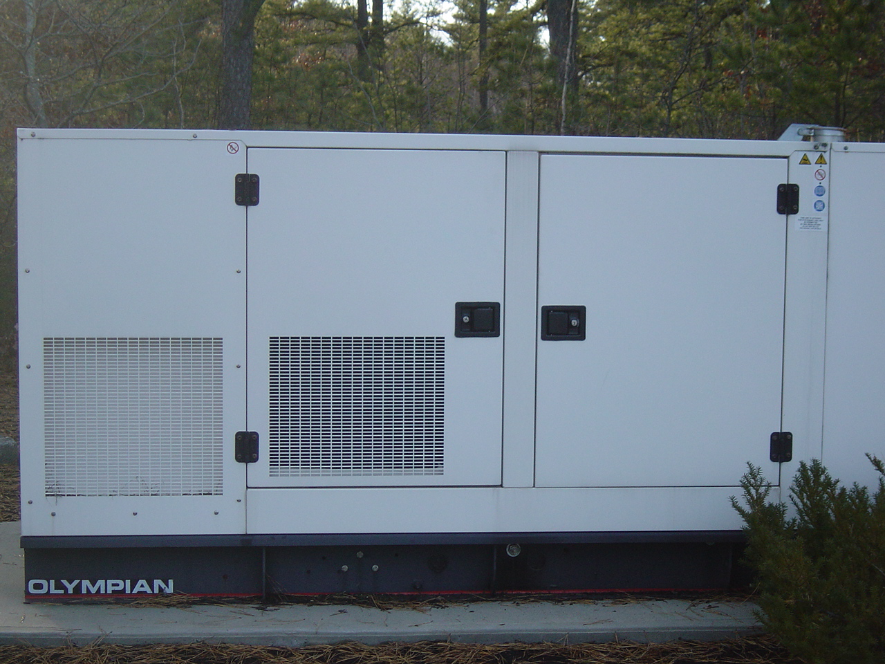 A large white Olympian standby generator seen from the side.