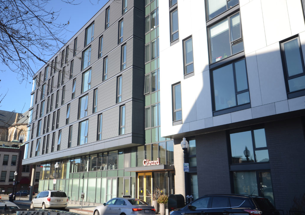 A completed mixed-use residential building with a ground-floor restaurant, seen from the sidewalk.