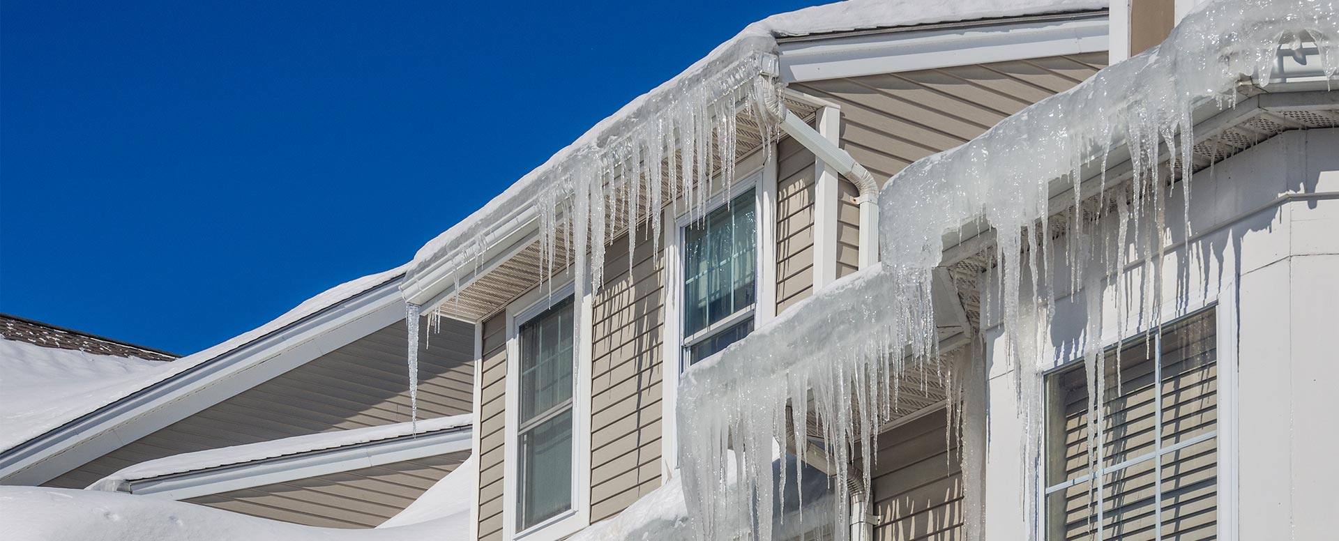 Icicles and an ice dam hanging from a house eave
