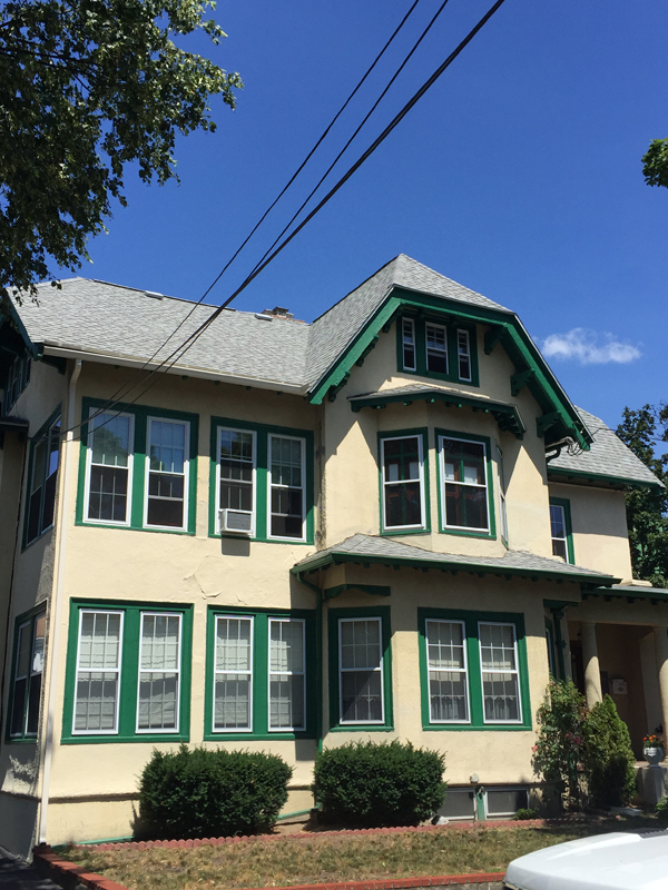 Cream two-family house with green trim and a new roof