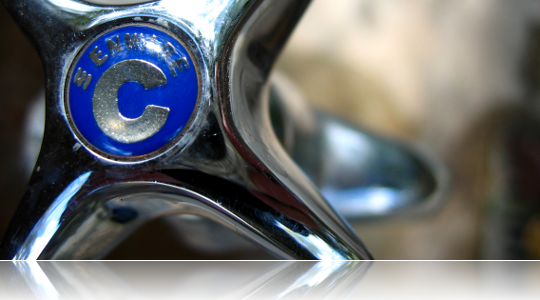 Close-up of a polished chrome faucet handle with a blue cold index button