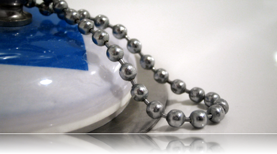Chrome ball chain resting on a white porcelain sink stopper